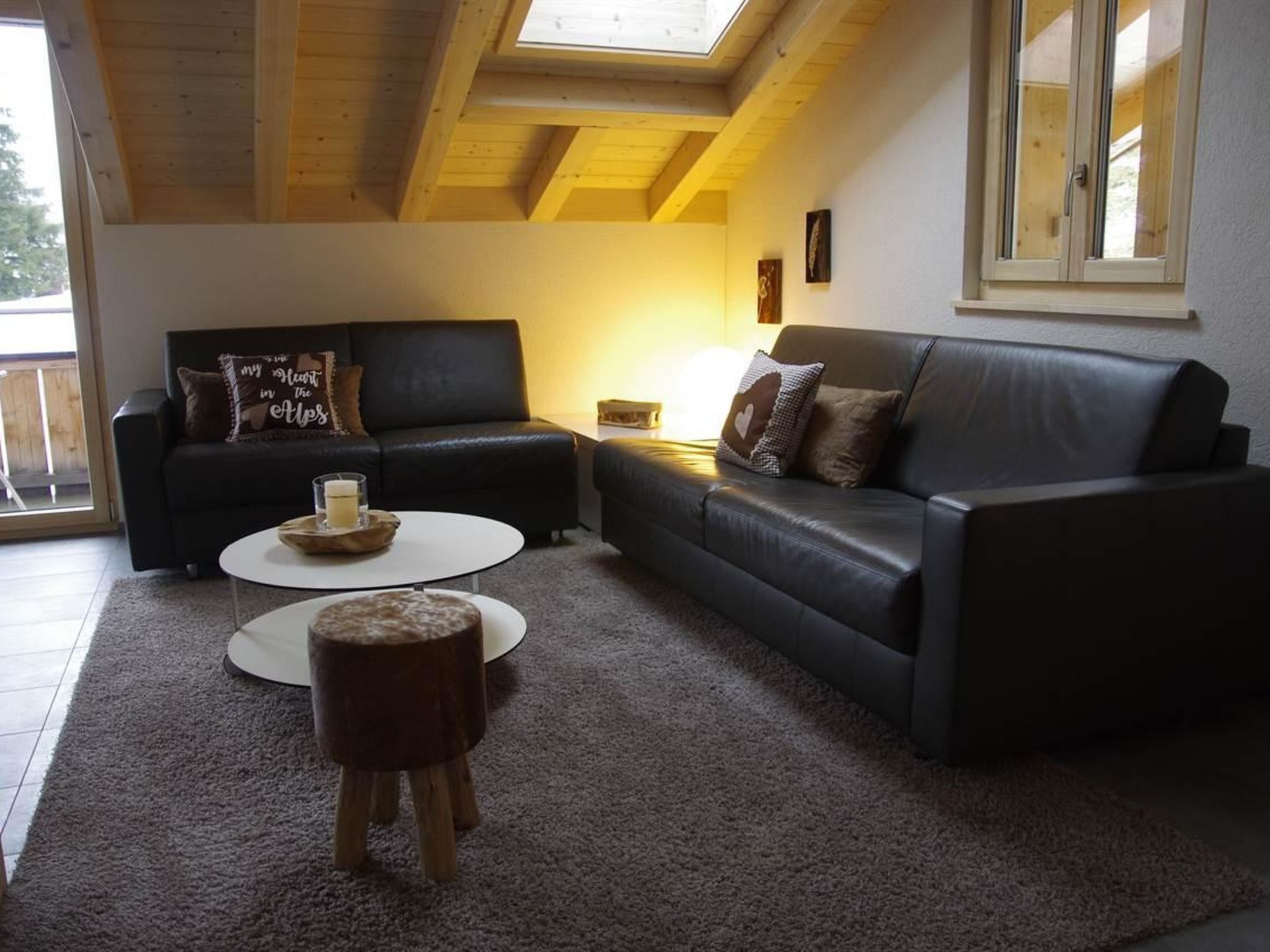Ein Wohnzimmer mit zwei schwarzen Ledersofas, einem runden Couchtisch und einem kleinen Holzschemel.