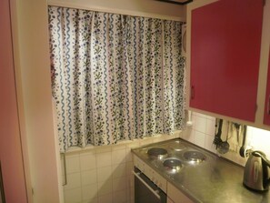 Eine Küche mit einem Herd, einem Wasserkocher und einem roten Schrank.