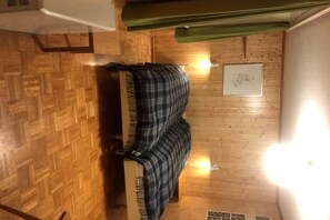 Une pièce avec un plancher en bois, un canapé, une lampe fixée au mur et un tableau encadré.