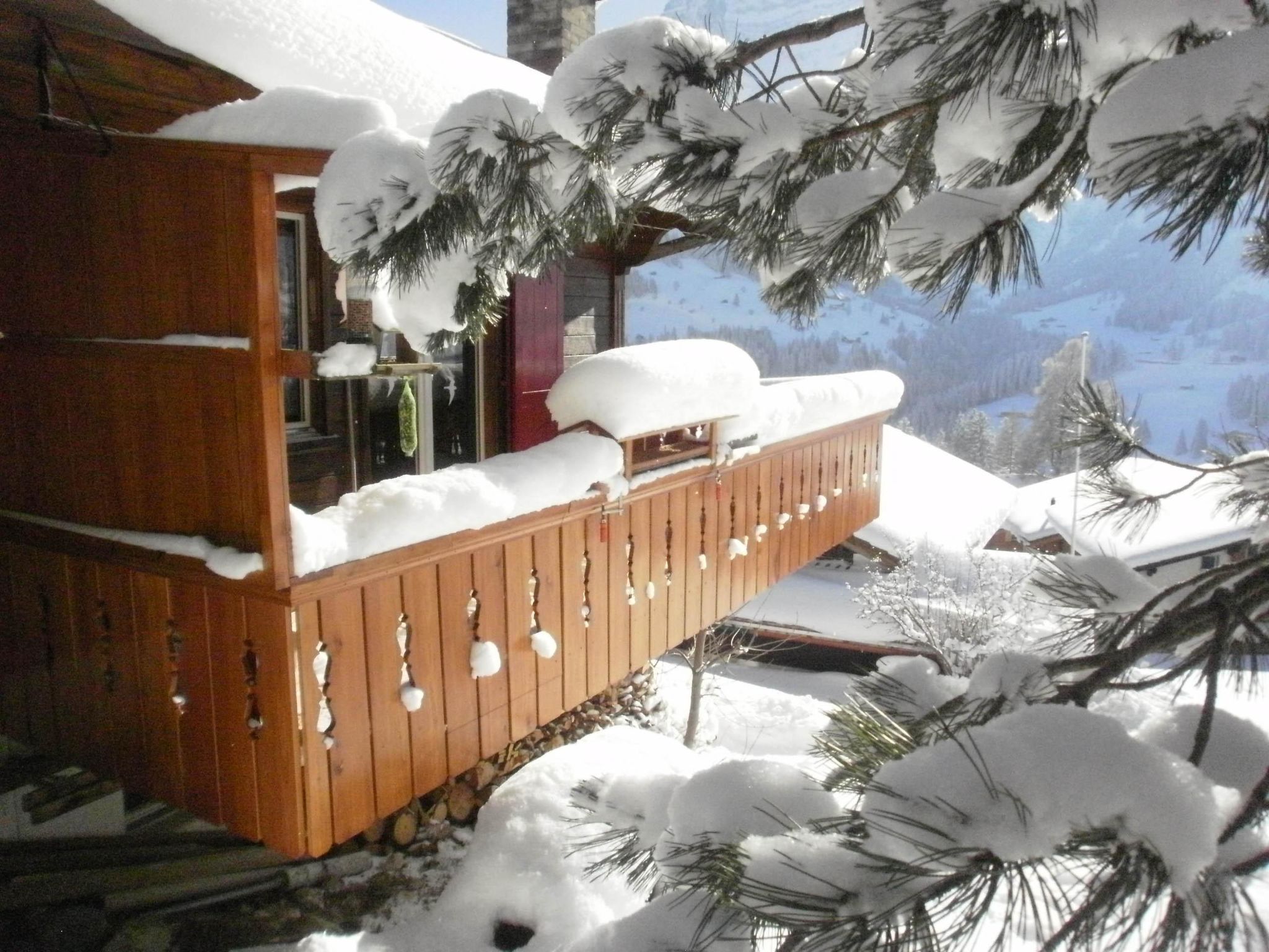 A wooden cabin with a balcony, surrounded by snow-covered trees.
