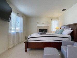 A bedroom with a bed, a television, a fireplace, and a window with curtains. - Big family home near the park (Elk Grove)