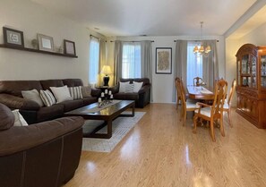 A living room with a brown sofa, a coffee table, a dining table with chairs, and a wooden cabinet. - Big family home near the park (Elk Grove)