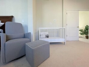 A room with a grey sofa, a white crib, and a door. - Big family home near the park (Elk Grove)