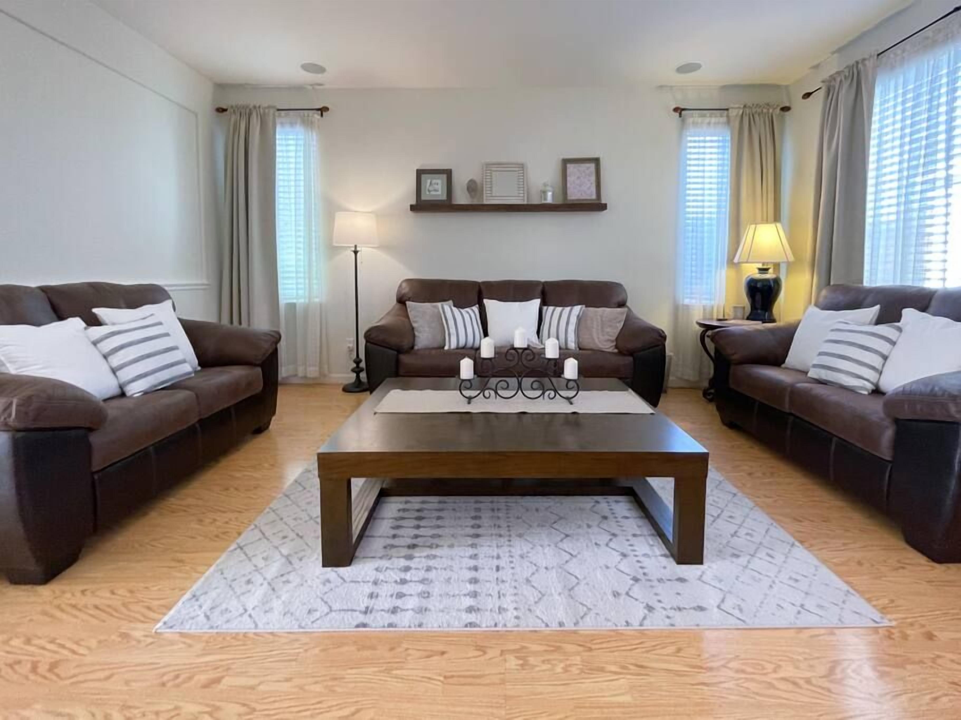 Una sala de estar con dos sofás marrones, una mesa de centro de madera y una alfombra estampada.