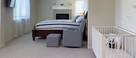 Ein Schlafzimmer mit einem Bett, einem Kinderbett, einem Fernseher und einem Kamin.