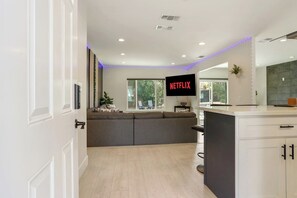 A modern living room with a sofa, a kitchen island, and a large window. - Clean Modern Living | College-Glen Gem Near River (Sacramento)