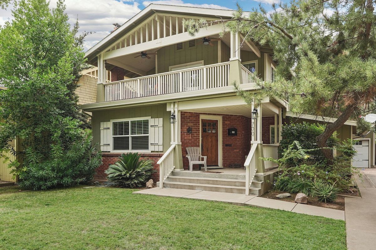 A two-story house with a front porch, a balcony on the upper floor, and a brick facade.