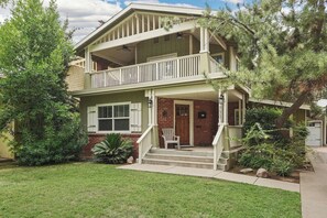 Une maison à deux étages avec un porche à l’avant, un balcon à l’étage supérieur et une façade en briques.