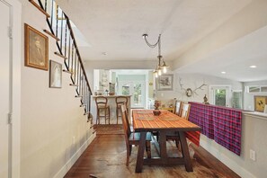 Ein Essbereich mit einem Holztisch, Stühlen und einer Tischdecke mit Muster.