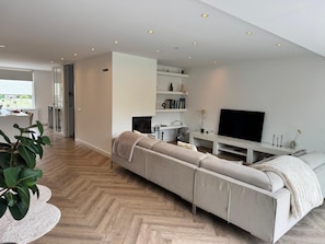 A modern living room with a sofa, television, and a fireplace.
