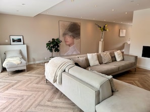 A modern living room with a sectional sofa, a small chair, and a potted plant.