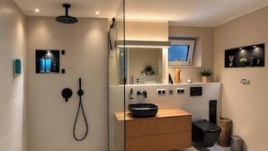 Ein modernes Badezimmer mit Duschkabine aus Glas, einem Holzbadezimmer-Möbelstück, einem schwarzen Waschbecken und einem Spiegel über dem Waschtisch.