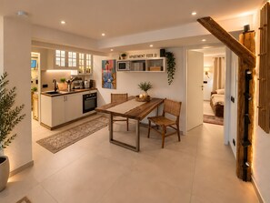 A modern kitchen with white cabinets, a wooden dining table, and a kitchen island.