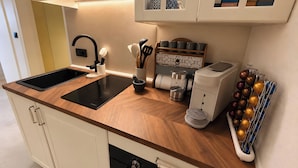 Eine moderne Küche mit einer schwarzen Induktionskochplatte, einer integrierten Spüle und einer Kaffeemaschine.