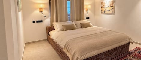 Una camera da letto con un letto grande, due lampade a parete, una finestra con tende e un tappeto decorato.
