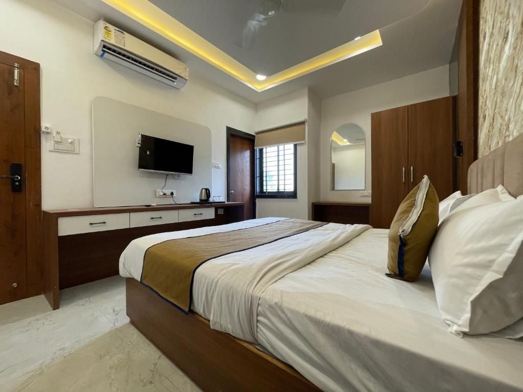 Una habitación de hotel con cama, mesita de noche, televisor, armario y aire acondicionado.