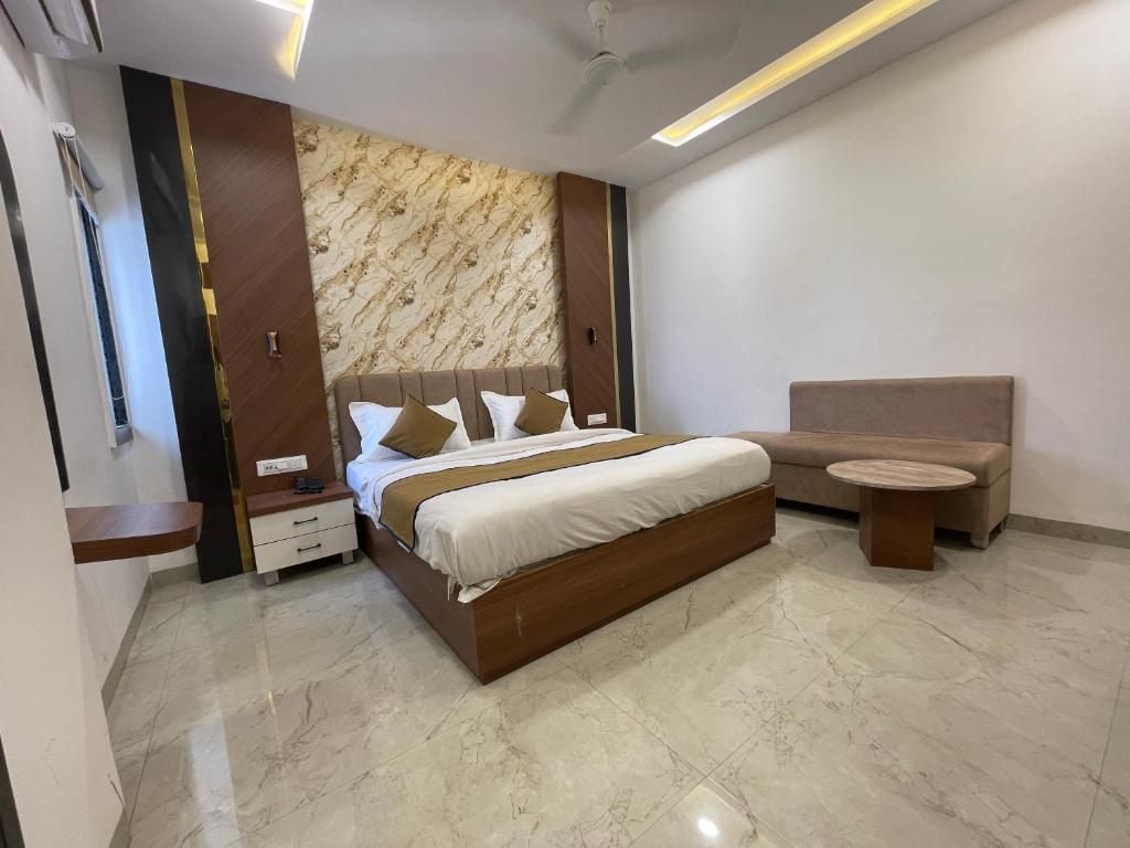 A modern bedroom with a large bed, bedside tables, a sofa, and a small round table.