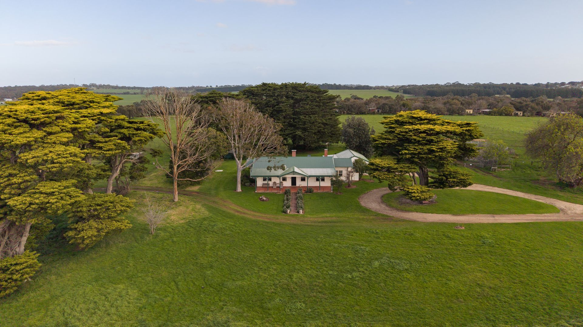 A large house with a green roof, surrounded by a well-maintained lawn and trees.