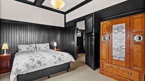 A bedroom with a bed, bedside tables, a wardrobe, and a door with a decorative glass panel. - Byfrons Phillip Island Road (Cowes)
