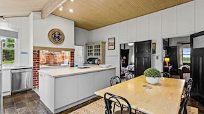 A kitchen with a central island, a dining area with a table, and a brick wall. - Byfrons Phillip Island Road (Cowes)