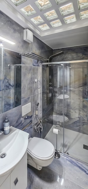 Une salle de bain moderne avec une douche à parois de verre, un lavabo blanc et des toilettes.