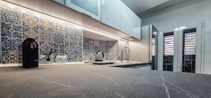 A modern kitchen with a marble countertop, patterned backsplash, and stainless steel appliances.