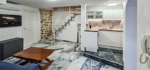 A compact kitchen with a stone accent wall, a built-in stove, and a small dining area with a wooden table.