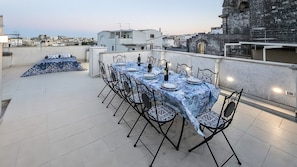 Une terrasse sur le toit avec une table à manger pour six personnes, entourée de chaises.