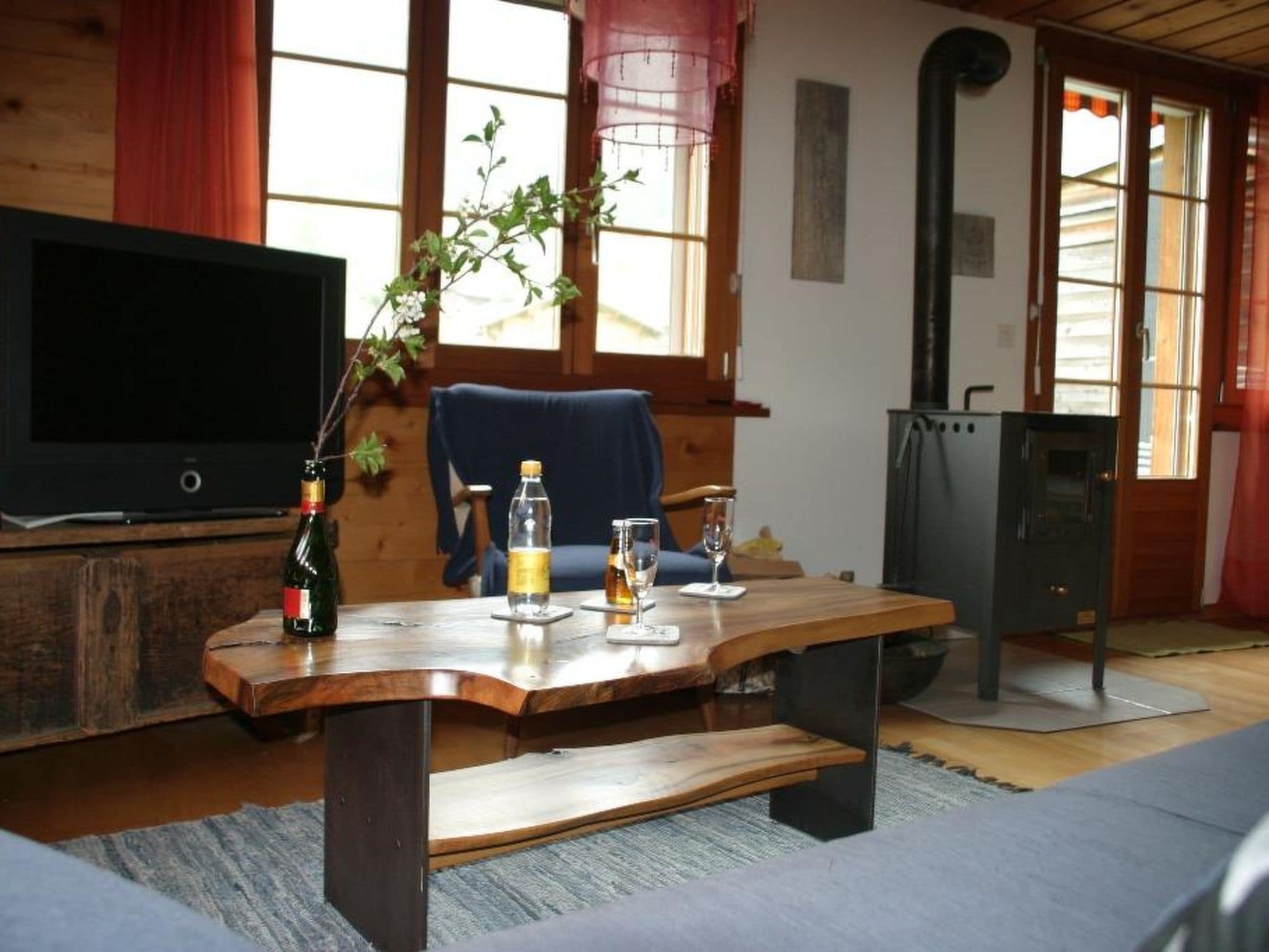 Ein gemütliches Wohnzimmer mit Couchtisch aus Holz, Fernseher, Sessel und Kamin.