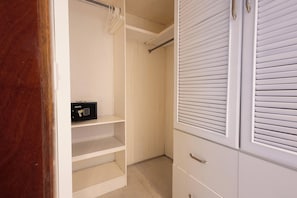 A walk-in closet with white shelving, a black safe, and a sliding door with blinds. - Estrella Del Mar F4_400Mbps_BBQ_Pool_Walk to Beach (Punta Cana)