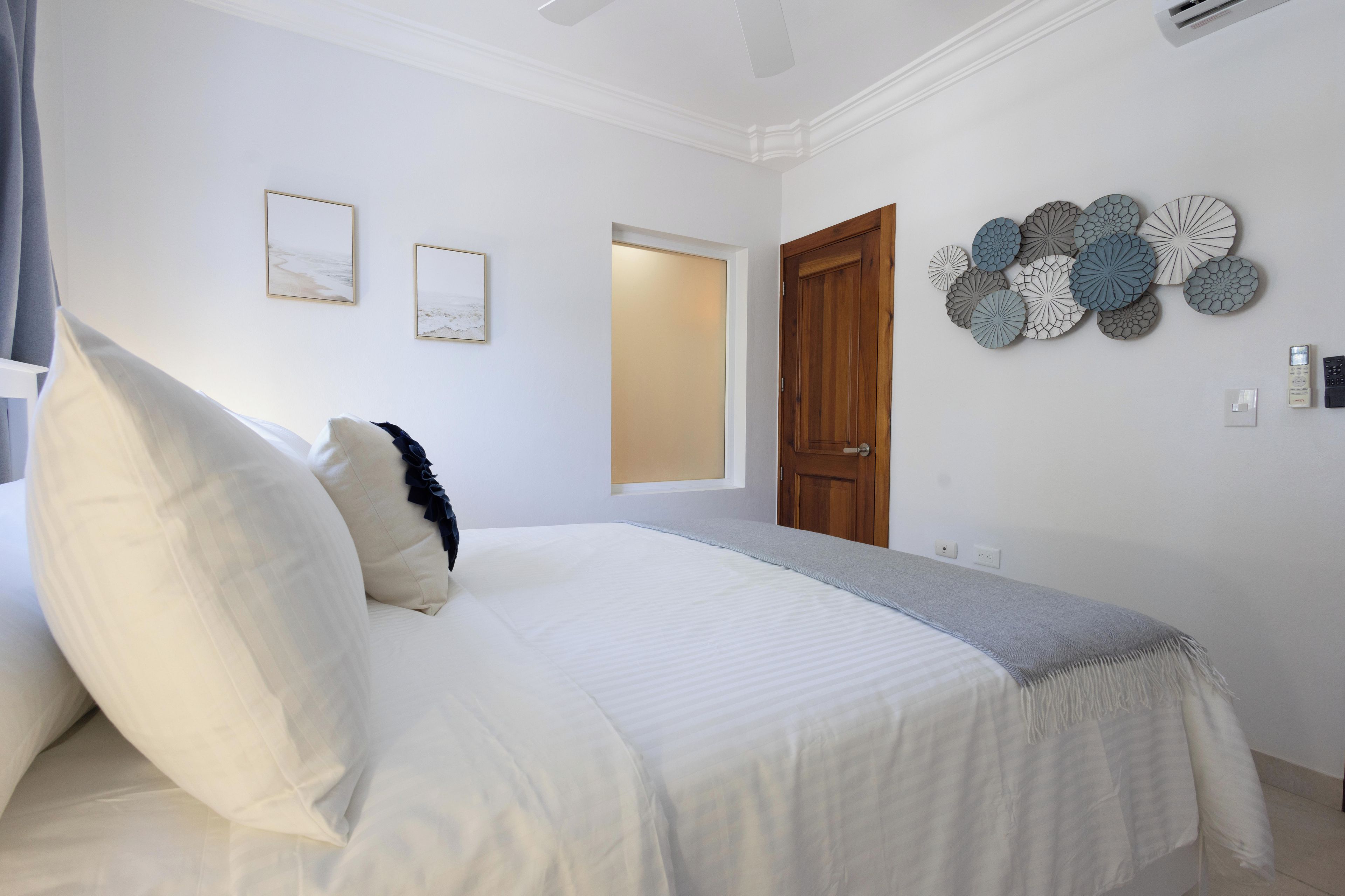Ein Schlafzimmer mit einem Bett, zwei gerahmten Bildern an der Wand, einer Holztür und einer Wanddekoration.