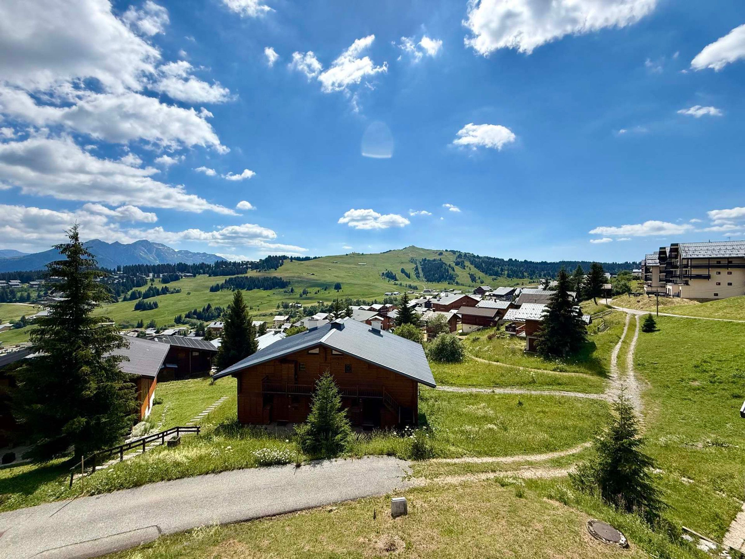 Un pittoresco borgo rurale con case in legno tradizionali, cielo sereno e montagne sullo sfondo.