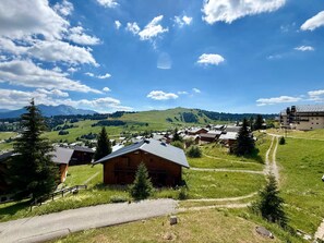 A rural village with traditional wooden houses, a clear sky, and mountains in the background. - Apartment with slope view - 5 guests (Les Saisies)
