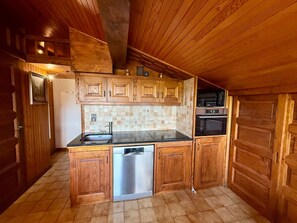 A kitchen with wooden cabinets, a stainless steel dishwasher, and a microwave. - Apartment with slope view - 5 guests (Les Saisies)