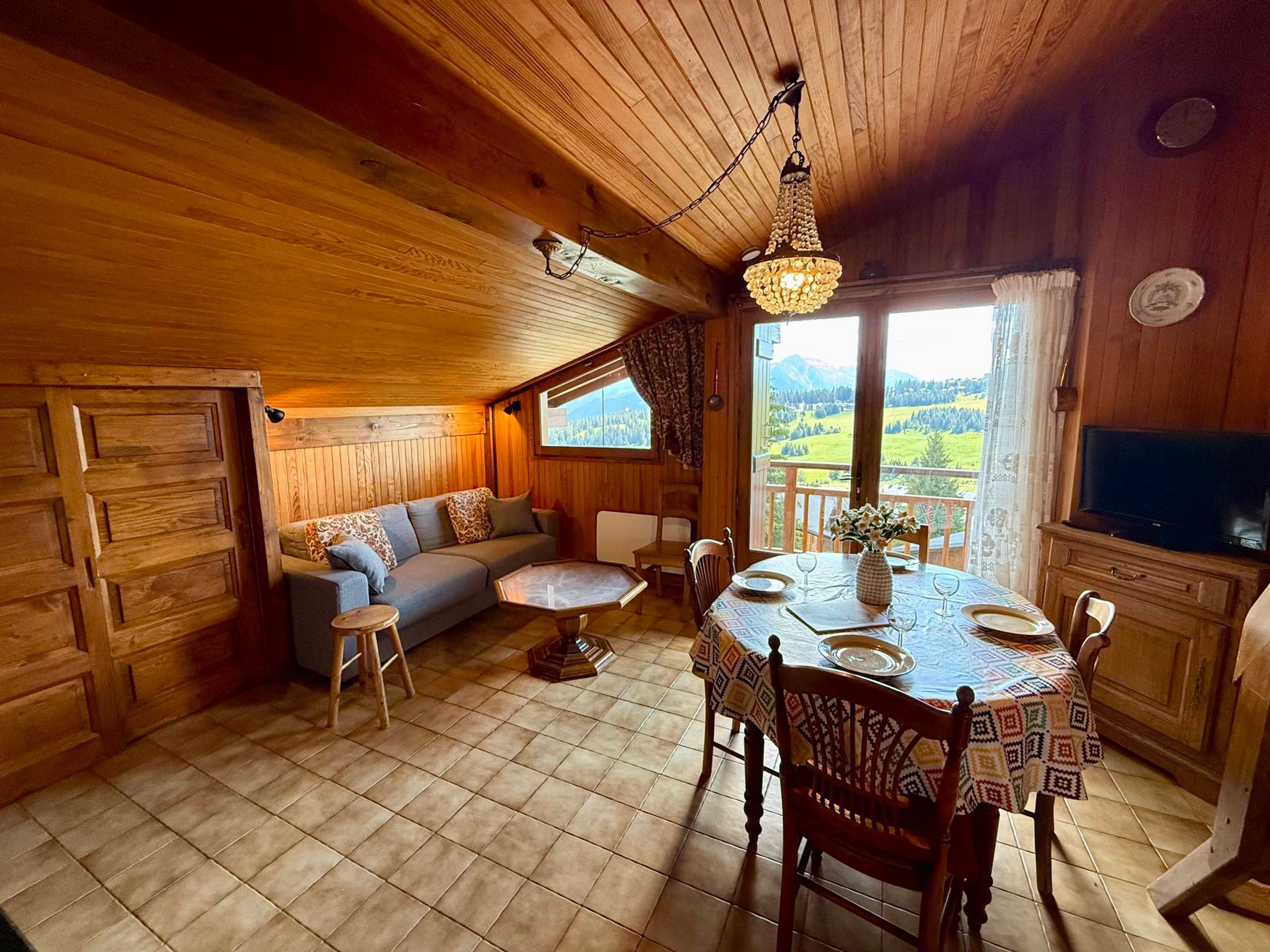 A cozy cabin interior with a dining area, sofa, and a view of the outdoors.