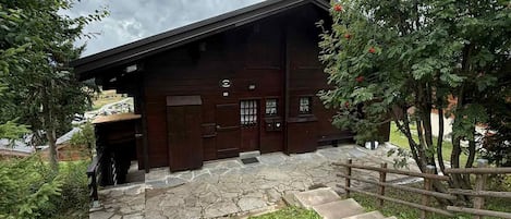 A wooden building with a stone-paved entrance and a wooden fence.