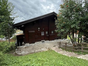 Un edificio in legno con ingresso lastricato in pietra e una recinzione di legno.