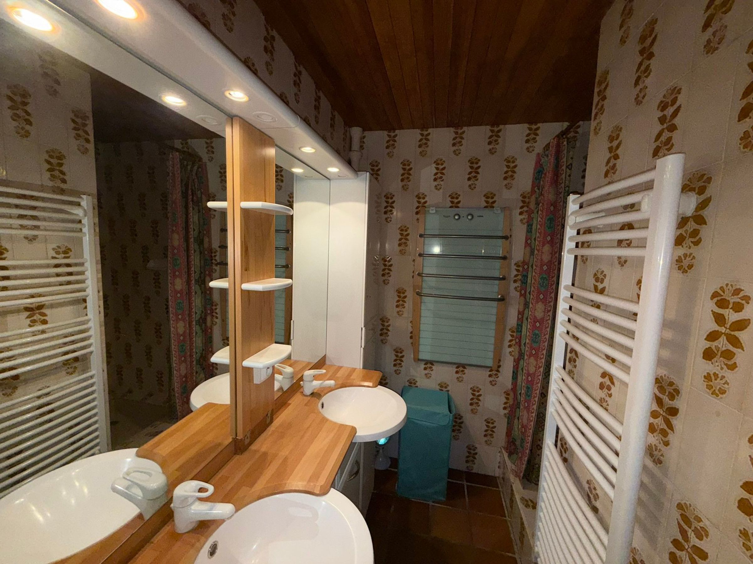 Een badkamer met twee wastafels, een spiegel, een handdoekhouder en een douche.