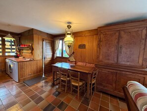 Ein Holzinterieur mit Esstisch, Stühlen, einer Waschmaschine und einem Deckenventilator.