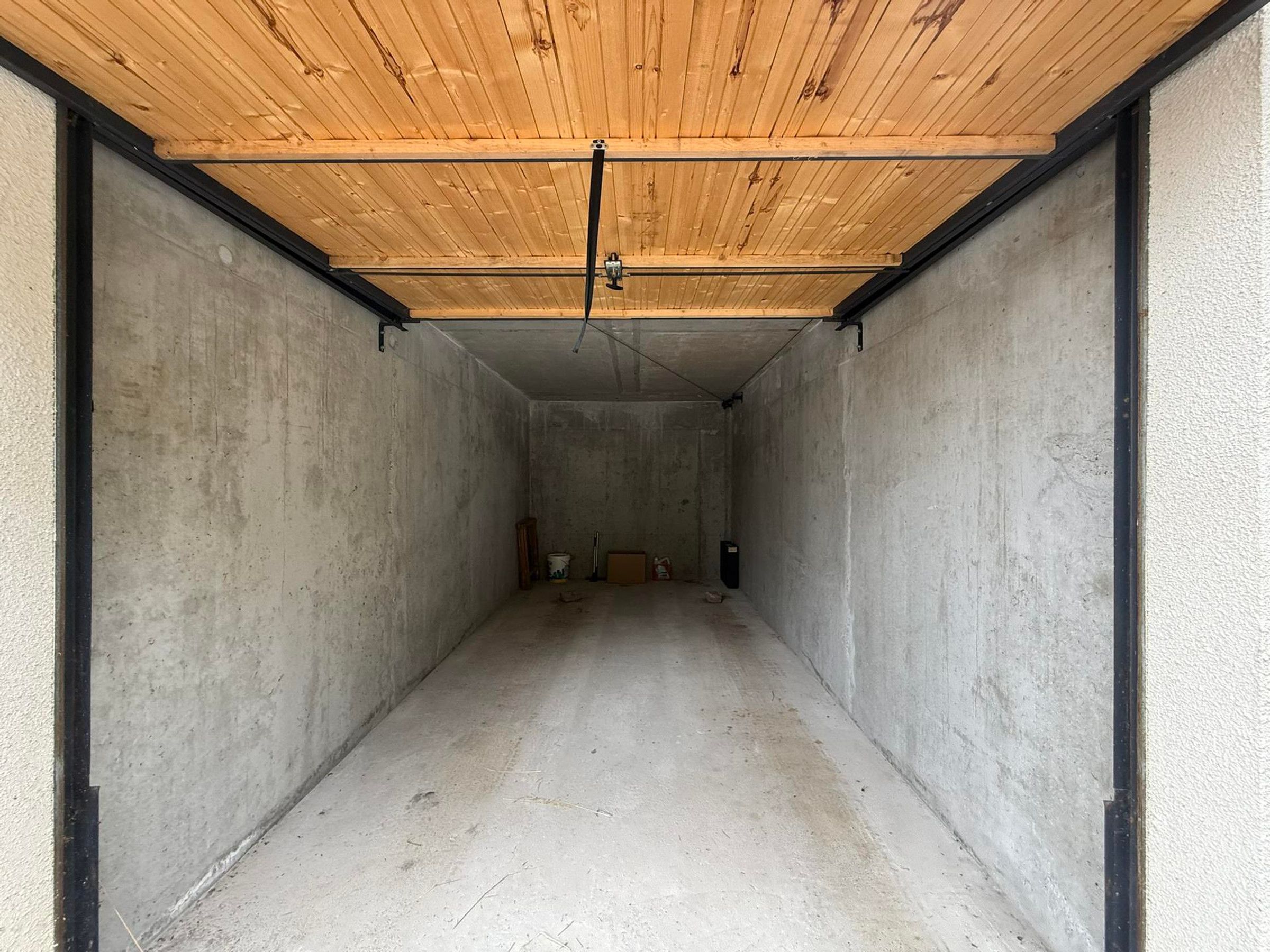 Ein Raum mit Betonwänden, einer Holzbalkendecke und einem Betonboden.