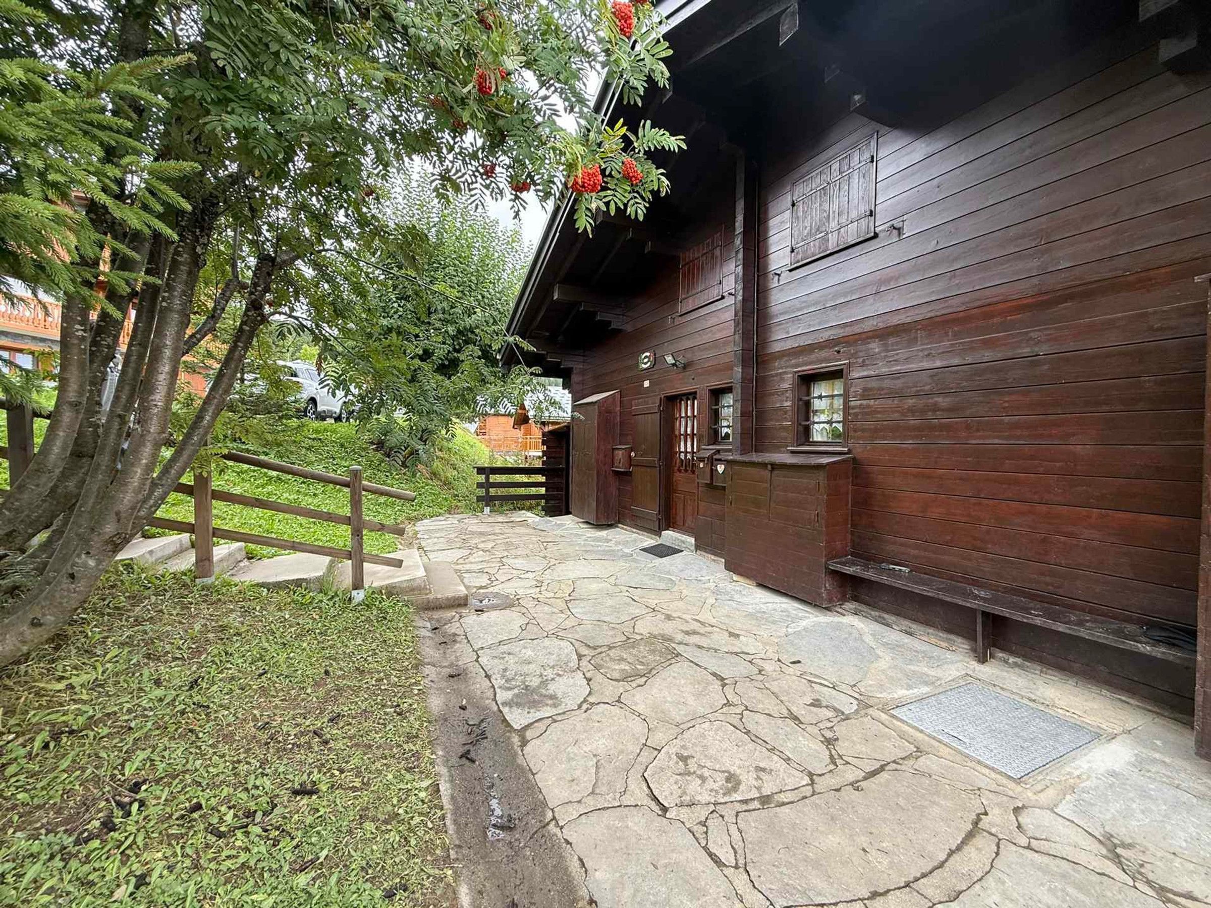 Un bâtiment en bois avec un chemin de pierre menant à une porte en bois.