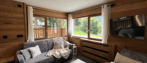 A cozy living room with a sofa, a coffee table, and a television mounted on the wall.
