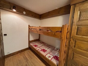 A bunk bed with a patterned mattress, wooden beams, and a door with a panel design. - Spacious apartment slope views - 8 guests (Les Saisies)