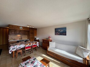 A compact living space with a kitchenette, a dining area, a sofa, and a small table. - Spacious apartment slope views - 8 guests (Les Saisies)