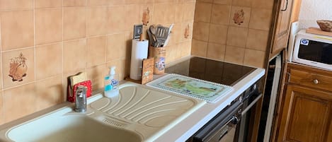 Une cuisine équipée d’un évier, d’un four à micro-ondes et de meubles de rangement en bois.
