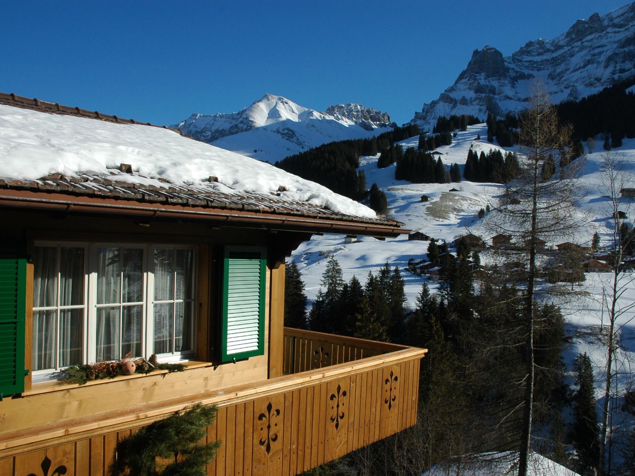 A chalet with a balcony overlooking a snowy mountain landscape.