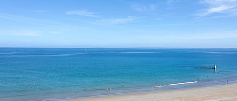 Une plage avec une eau d’un bleu limpide et un rivage sablonneux.