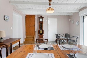 A dining area with a wooden table, chairs, a clock, and a ceiling fan.