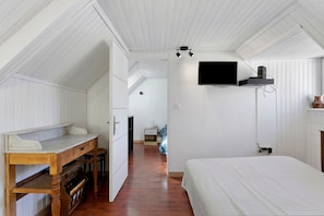 Un dormitorio con cama, escritorio y televisión instalada en la pared.