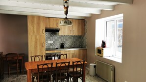 Een keuken met houten kastjes, een decoratieve spatwand, een eettafel met stoelen en een raam met uitzicht.
